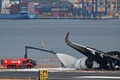 海上保安庁の航空機と衝突した日本航空（JAL）の旅客機と水をかける消防車。東京国際（羽田）空港で（2024年1月3日撮影）。(c)Richard A. Brooks / AFP
