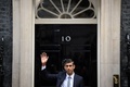 英ロンドンの首相官邸前で手を振るリシ・スナク新首相（2022年10月25日撮影）。(c)Daniel LEAL / AFP 