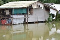 タイ南部ナラティワット県で、浸水地域の住宅から外を眺める住民（2022年12月19日撮影）。(c)Madaree TOHLALA / AFP