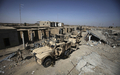 戦闘で激しく破壊されたアフガニスタン南部ヘルマンド（Helmand）州マルジャ（Marjah）の市場に止まった軍の装甲車（手前、2010年2月17日撮影）。(c)AFP/Altaf Qadri