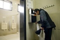 中国・北京の観光名所「天壇（てんだん）」の公衆トイレに導入された、顔認証システムを取り入れたトイレットペーパーの配布装置を利用する男性（2017年3月21日撮影）。(c)AFP/WANG Zhao