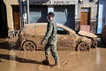 スペイン東部バレンシア自治州で、洪水で損傷した自動車の横を歩く兵士（2024年11月2日撮影）。(c)JOSE JORDAN / AFP