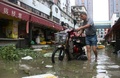 台風14号が上陸した中国・福建省のアモイで、冠水した通りでバイクを押す男性（2016年9月15日撮影）。(c)AFP