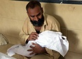 パキスタン南部カラチにある遺体安置所で、熱波により亡くなった3歳の息子の遺体を抱く男性（2015年6月22日撮影）。(c)AFP/Rizwan TABASSUM
