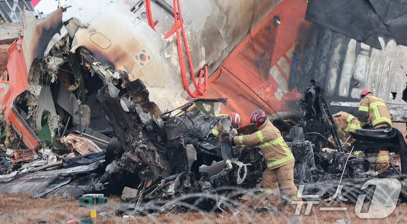 30日午前、務安国際空港で旅客機の残骸を捜索する消防隊員ら(c)news1