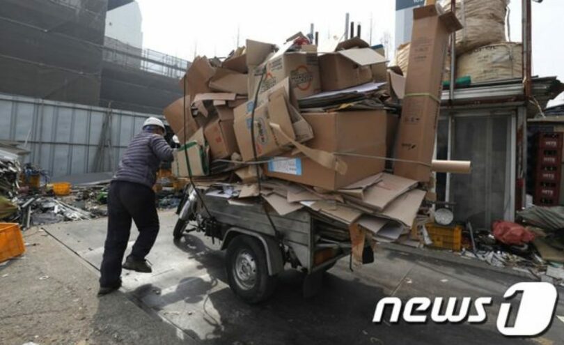 オートバイの荷車に古紙などを積んでいる高齢者(c)news1