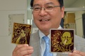 フランソワ・オランド(Francois Hollande)仏大統領（右）などをモチーフにした柄の太陽電池の試作品を手にする、東京大学（University of Tokyo）先端科学技術研究センター（Centre for Advanced Science）の瀬川浩司（Hiroshi Segawa）教授（2014年7月24日）。(c)AFP/Yoshikazu TSUNO