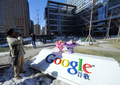 北京（Beijing）にあるグーグル・チャイナ（Google China）のオフィス前で、同社の看板に花束をそえてスローガンを叫ぶ男性（2010年1月13日撮影）。(c)AFP/GOH CHAI HIN