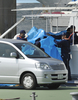 逮捕され海上保安庁の「ゆめかぜ（Yumekaze、右）」から車に移されるシー・シェパードの超高速抗議船アディ・ギル（Ady Gil）号船長のピーター・ベスーン（Peter Bethune）容疑者（青いシートの中、2010年3月12日撮影）。(c)AFP/Kazuhiro NOGI