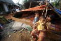 2007年9月14日、インドネシア・北ブンクル（North Bengkulu）州Ketahunで、倒壊した家の前にテントを建て避難する親子。(c)AFP/ADEK BERRY