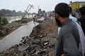 パキスタンのミルプール近郊で、地震により損壊した道路の脇に集まった人々（2019年9月25日撮影）。(c)AAMIR QURESHI / AFP