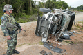 2007年6月22日、ナラティワット（Narathiwat）県で道路脇に仕掛けられた爆弾の被害を受けた軍用車の横で警備にあたる兵士。(c)AFP/Madaree TOHLALA