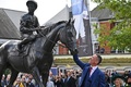 競馬、ブリティッシュ・チャンピオンズデー。会場のアスコット競馬場で除幕された自身の銅像に触れるフランキー・デットーリ騎手（2023年10月21日撮影）。(c)Glyn KIRK / AFP
