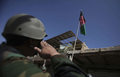 アフガニスタン南部ヘルマンド（Helmand）州マルジャ（Marjah）の市場の建物に掲揚されたアフガニスタン国旗に敬礼するアフガニスタン国軍の兵士（2010年2月17日撮影）。(c)AFP/Altaf Qadri