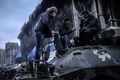 ウクライナの首都キエフ（Kiev）の独立広場（Independence Square）に放置された装甲車の上で休む人たち（2014年2月25日撮影）。(c)AFP/BULENT KILIC