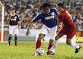 ホーチミン市で行われた親善試合で、元ベトナム代表のレー・フイン・ドゥック（%%Le Huynh Duc%%）を相手にボールをキープする元フランス代表のクリスティアン・カランブー氏（中央）。(c)AFP