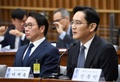 韓国・朴槿恵（パク・クネ）大統領の親友による国政介入疑惑に絡み、国会の聴聞会に呼ばれて証言するサムスン電子副会長の李在鎔（イ・ジェヨン）氏（右）とそれを聞くSKグループ会長の崔泰源（チェ・テウォン）氏（2016年12月6日撮影）。(c)AFP/JUNG YEON-JE