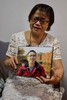 新型コロナウイルス感染症で亡くなった息子の写真を掲げる中国・武漢市在住の鍾漢能さん（2020年9月6日撮影）。(c)Hector RETAMAL / AFP