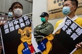 香港の警察署前で、中国の習近平国家主席を暗喩する「くまのプーさん」を描いたポスターを破る民主派の活動家ら（2020年5月24日撮影）。(c)AFP/ISAAC LAWRENCE