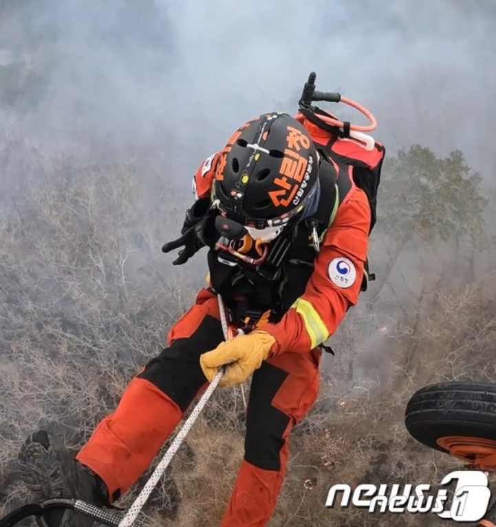 ロープを利用して山火事の中に飛び込む空中鎮火隊員（山林庁提供）(c)news1