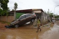 コートジボワールのアビジャンで、車の残骸のそばを歩く人々（2018年6月19日撮影）。(c)AFP PHOTO / Sia KAMBOU
