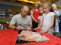 ロシア極東のハバロフスク（Khabarovsk）地方で夏期休暇中、子どもにサインを書くウラジーミル・プーチン（Vladimir Putin）首相（2010年8月27日撮影）。(c)AFP/RIA-NOVOSTI/ALEXEY DRUZHININ