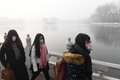スモッグに覆われた中国・北京で、マスクを着けて歩く女性ら（2017年1月1日撮影）。(c)AFP/GREG BAKER