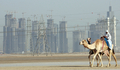 2007年４月2日、ドバイ（Dubai）で建設中の超高層ビル｢ブルジュ・ドバイ（Burj Dubai）｣の前を通るラクダのキャラバン。(c)AFP/KARIM SAHIB