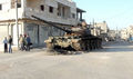 シリア中部ラスタン（Rastan）で、破壊され捨てられた戦車の横に立つ人びと（2012年3月10日撮影）。(c)AFP