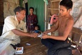 カンボジアのコンポンスプー州にある村で、患者に薬を渡す無免許医師のケン・モンさん（2015年2月27日撮影）。(c)AFP/TANG CHHIN SOTHY