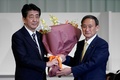 安倍晋三首相（左）から花束を受け取る菅義偉官房長官（2020年9月14日撮影）。(c)Eugene Hoshiko / POOL / AFP