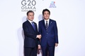 大阪で開催中の20か国・地域（G20）首脳会議の歓迎行事で、韓国の文在寅（ムン・ジェイン）大統領（左）を迎える安倍晋三首相（右、2019年6月28日撮影）。(c)Brendan Smialowski / AFP