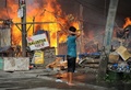 イスラム武装勢力の襲撃を受けたフィリピン南部ミンダナオ（Mindanao）島の商業都市サンボアンガ（Zamboanga）では、12日も治安当局と和平協議に応じないイスラム反政府勢力との戦いが2か所の戦線で続いている。同国政府は、炎に包まれた複数の地区を奪還した。

サンボアンガでは、4日間にわたる戦闘で数千人が避難を強いられている。フィリピン軍報道官によると、同市のサンタカタリナ（Santa Catalina）地区では、治安部隊が進軍する中、家々が炎に包まれた。

警察の支援を受けた少なくとも1500人の兵士が、サンボアンガ郊外のイスラム教徒が多く住む6地区を包囲。これらの地域では、反政府勢力「モロ民族解放戦線（MNLF）」のメンバー約180人が、9日に攻撃を開始して以降潜伏を続けている。反政府勢力は数十人の人々を「人間の盾」にしているため、市民が負傷することを避けたい治安部隊との間でこう着状態が続いている。

写真はサンボアンガで火に包まれる家々を見る地元住民（2013年9月12日撮影）。(c)AFP/TED ALJIBE