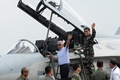 フィリピン・パンパンガ州のクラーク空軍基地で、到着した韓国製戦闘機「FA-50」を視察し、報道陣に向かって手を振る、ボルテア・ガズミン国防相（左、2015年11月28日撮影）。(c)AFP/TED ALJIBE