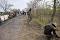 ウクライナ東部スラビャンスク（Slavyansk）近郊の検問所で起きた銃撃戦の現場を調べる武装した親ロシア派の男性ら（2014年4月20日撮影）。(c)AFP/GENYA SAVILOV