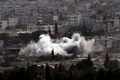 シリア北部アインアルアラブ（Ain al-Arab、クルド名：コバニ、Kobane）から立ちのぼる砲撃の煙。国境の反対側トルコ・シャンルウルファ（Sanliurfa）県の村ムルシトピナル（Mursitpinar）より（2014年10月13日撮影）。(c)AFP/ARIS MESSINIS