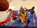 08-09NBA西カンファレンスプレーオフ1回戦、ロサンゼルス・レイカーズ（%%Los Angeles Lakers%%）対ユタ・ジャズ（%%Utah Jazz%%）第5戦。試合はレイカーズが107-96で勝利し、通算戦績を4勝1敗として同準決勝に進んだ。レイカーズは、コービー・ブライアント（%%Kobe Bryant%%）が両チーム最多の31得点を奪って勝利し、5戦目でジャズとのプレーオフ1回戦を制した。写真はジャズのメメット・オコワー（%%Mehmet Okur%%、左）を抑えてシュートを放つレイカーズのコービー・ブライアント（中央）。（2009年4月27日撮影）(c)AFP/Getty Images/Kevork Djansezian