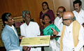写真は、タミル・ナードゥ州のカライニャル・M・カルナーニディ（%%Kalaignar M Karunanidhi%%）首相（右2）から賞金150万ルピー（約400万円）の小切手を受け取るソウンダラジャン（左）（2006年12月18日撮影）。(c)AFP/Seshadri SUKUMAR