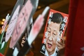 香港で、林鄭月娥（キャリー・ラム）行政長官と中国の習近平国家主席が描かれたプラカードを見せる民主派活動家（2019年12月18日撮影）。(c)Philip FONG / AFP