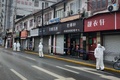 中国・上海の黄浦区で、隔離対象となった住宅街周辺を封鎖する防護服姿の警察官ら（2021年1月21日撮影）。(c)STF / AFP