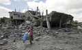 パレスチナ自治区ガザ地区（Gaza Strip）南部ラファ（Rafah）の難民キャンプ近くで、ボールと鳥かごを持って建物のがれきの中を避難する子ども（2014年8月4日撮影）。(c)AFP/MAHMUD HAMS