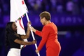パリ五輪閉会式。体操女子米国代表のシモーネ・バイルス（左）に五輪旗を手渡すロサンゼルスのカレン・バス市長（2024年8月11日撮影）。(c)Franck FIFE/ AFP
