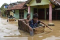 インドネシア・西ジャワ州バンドンの洪水した通りを廃棄された冷蔵庫を使って移動する子ども。豪雨で川が氾濫し、多くの家屋が浸水した（2025年3月16日撮影）。(c)Timur Matahari / AFP