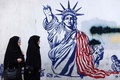 イラン・テヘランで、旧米国大使館の外壁に描かれた、たいまつを持つ腕が壊れた自由の女神像の絵の横を歩く女性（2024年11月6日撮影）。(c)ATTA KENARE / AFP