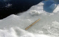 ロシア・チェリャビンスク（Chelyabinsk）州のチェバルクリ湖（Lake Chebarkul）で、表面の氷に開いた直径6メートルほどの穴のそばにある小さな物体とその横に置かれた定規（2013年2月15日撮影）。(c)AFP/CHELYABINSK REGION POLICE DEPARTMENT