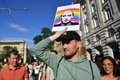 ハンガリーの首都ブダペストの議会前で、ロシアのウラジーミル・プーチン大統領の写真を掲げ、未成年に対する同性愛の「助長」行為を禁ずる法改正案に抗議する人（2021年6月14日撮影）。(c)GERGELY BESENYEI / AFP