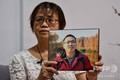 新型コロナウイルス感染症で亡くなった息子の写真を掲げる中国・武漢市在住の鍾漢能さん（2020年9月6日撮影）。(c)Hector RETAMAL / AFP