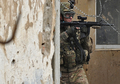 群集が集まったアフガニスタンのバグラム米空軍基地（Bagram Airbase）の門の前で、銃を構える米兵（2012年2月21日撮影）。(c)AFP/Massoud HOSSAINI
