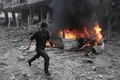 シリア政府軍とロシア軍によるものとされる爆撃があったシリア首都ダマスカス近郊の東グータで、炎上する乗用車の脇を駆け抜ける男性（2018年1月6日撮影）。(c)AFP PHOTO / ABDULMONAM EASSA
