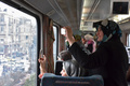 シリア・アレッポ東部で、荒廃した地区を走行する列車から外の写真を撮る女性ら（2017年1月25日撮影）。(c)AFP/George OURFALIAN